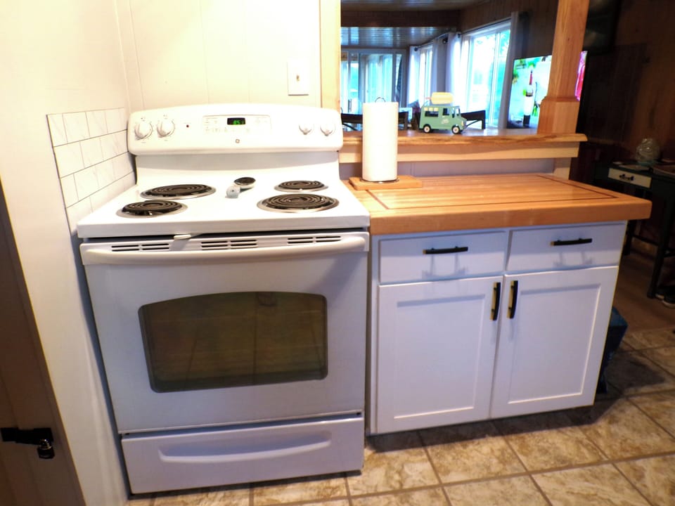 Electric range/oven. Butcher block cabinet with cookware provided.