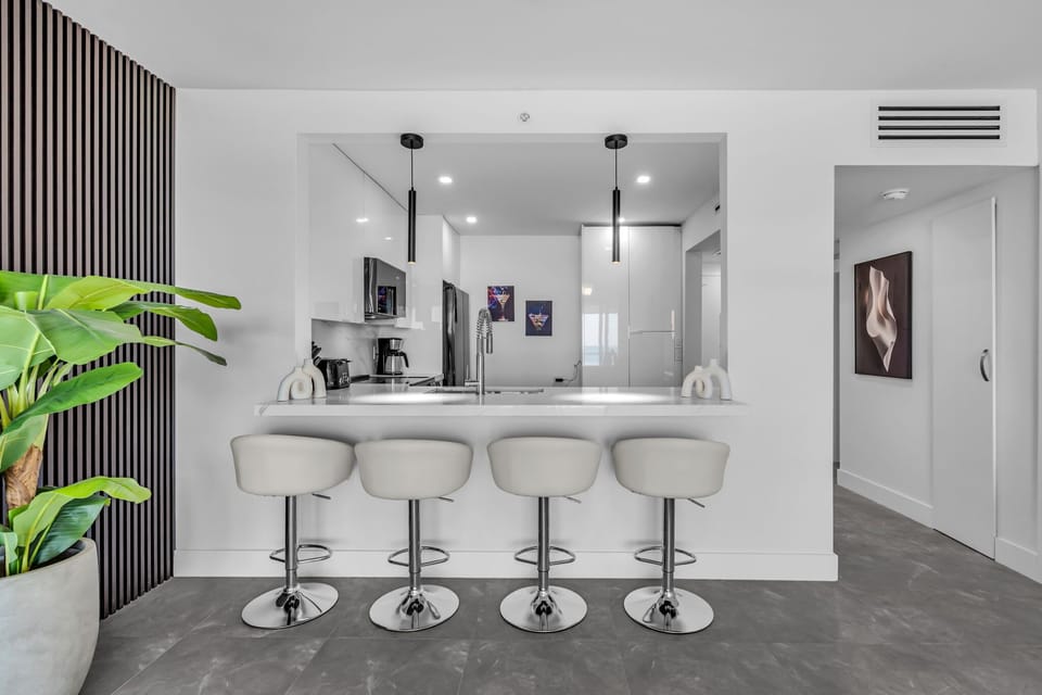 This chic, open-concept dining space maximizes every inch of style and functionality. In place of a traditional dining table, guests can enjoy meals at the modern breakfast bar, which features four elegant, swivel barstools and sleek pen