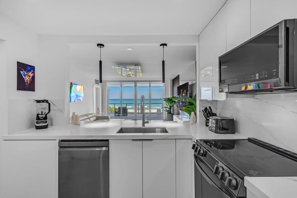 Prepare gourmet meals in this sleek, ultra-modern kitchen featuring high-end stainless steel appliances and crisp white cabinetry. The open layout keeps you connected to the light-filled living area and ocean views.