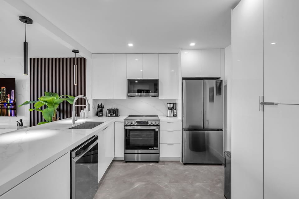 Prepare gourmet meals in this sleek, ultra-modern kitchen featuring high-end stainless steel appliances and crisp white cabinetry. The open layout keeps you connected to the light-filled living area and ocean views.