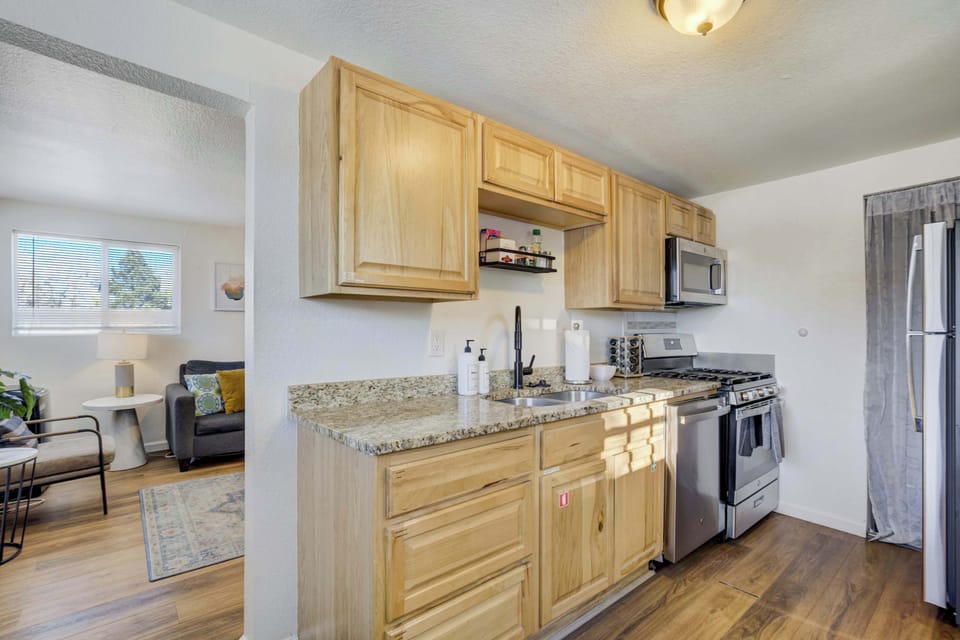 This fully stocked kitchen features warm wood cabinetry and granite countertops arranged in a practical layout. It’s equipped with modern appliances and flows seamlessly into the living area for easy socializing.