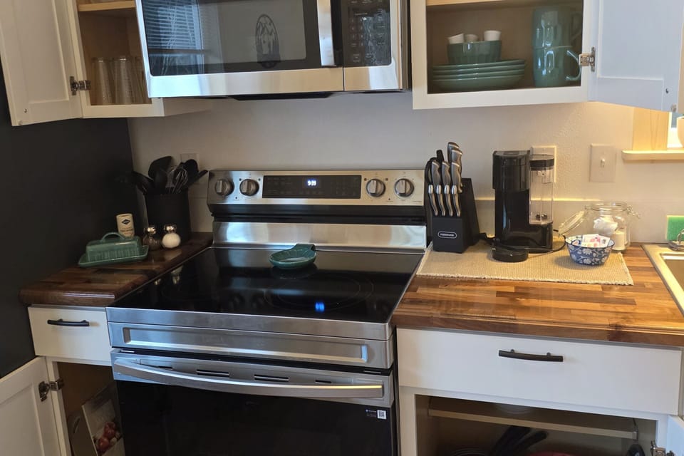Fully stocked kitchen includes an electric range, microwave, refrigerator, and Keurig.