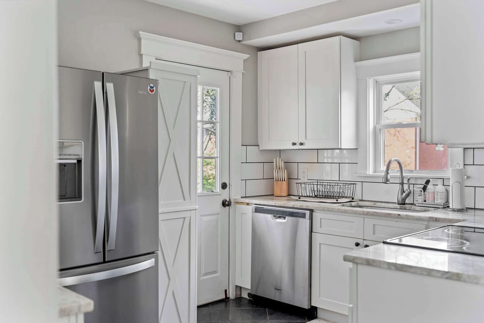 Modern kitchen w/ stainless fridge, sleek counters & bright cabinetry

