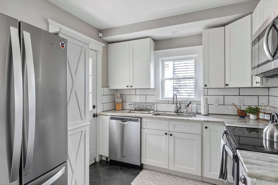 Clean kitchen w/ white cabinets, ample counter space & modern finishes