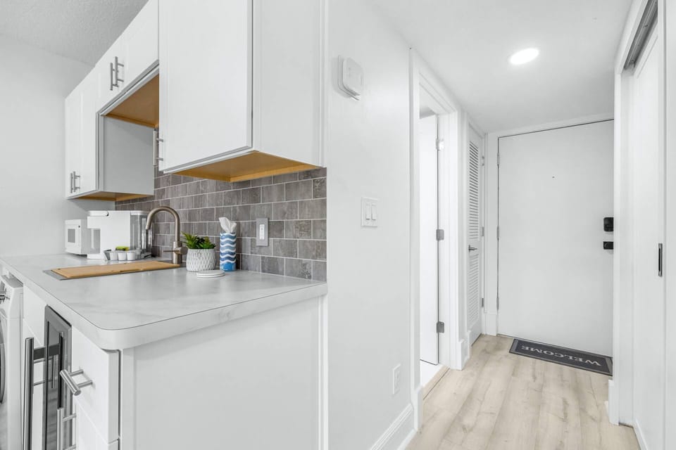 Modern kitchenette with sleek countertop, leading to the bright entryway and hallway.