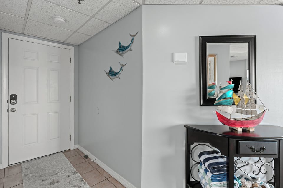Clean, white hallway with convenient storage and coastal wall accents.