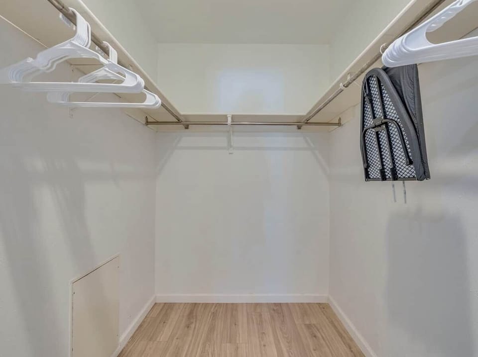 Keep your belongings organized in this spacious walk-in closet. It offers plenty of hanging space with built-in shelving and includes an ironing board for your convenience.
