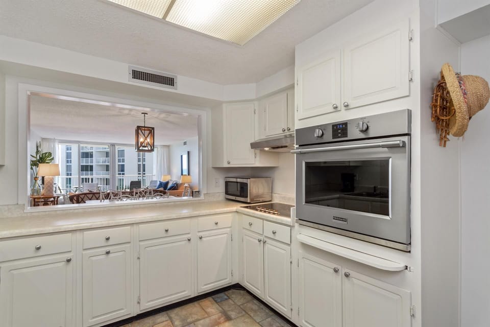 Your fully equipped kitchen features stainless steel appliances and white cabinetry, with a pass-through opening to the bright living area.