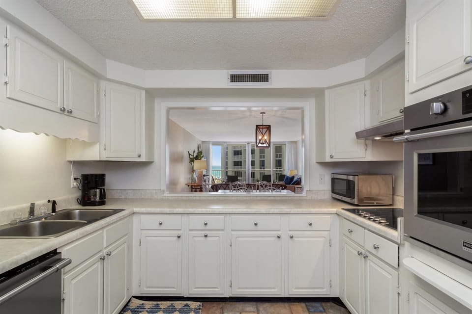 Prepare delicious meals in this bright, fully-equipped kitchen featuring white cabinetry and modern appliances.