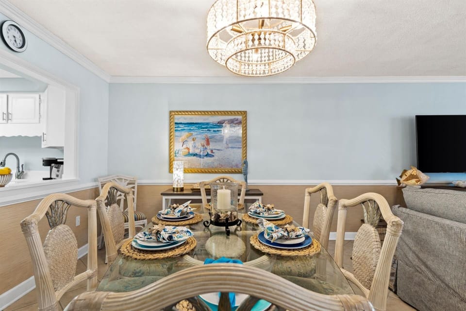 Your elegant dining room features a crystal chandelier, coastal artwork, and beautifully set table where you'll create memorable meals together.