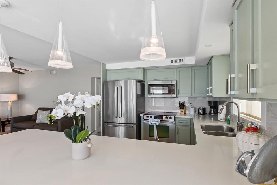 Step into your sleek kitchen featuring sage-green cabinets, granite countertops, and premium stainless appliances—perfect for preparing memorable meals.