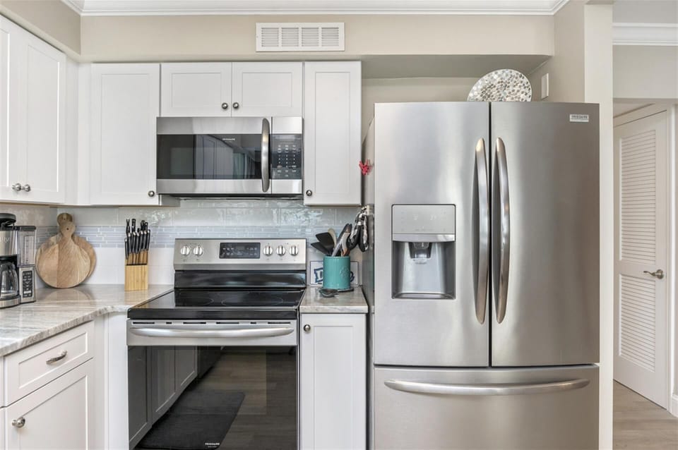 Your fully equipped kitchen features stainless steel appliances and bright white cabinetry, perfect for preparing meals during your stay.