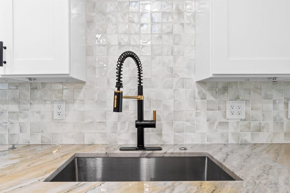 Prepare your favorite meals with this sleek kitchen featuring marble counters and modern fixtures.