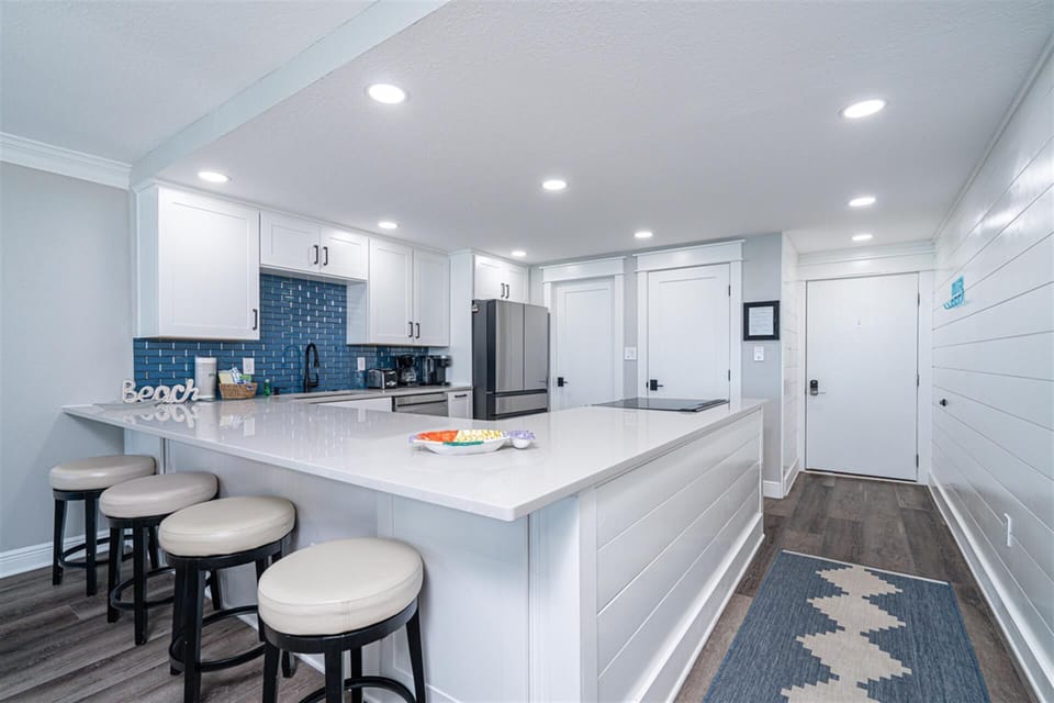 Your modern kitchen features white quartz counters, blue subway tile backsplash, and stainless appliances for effortless meal prep.