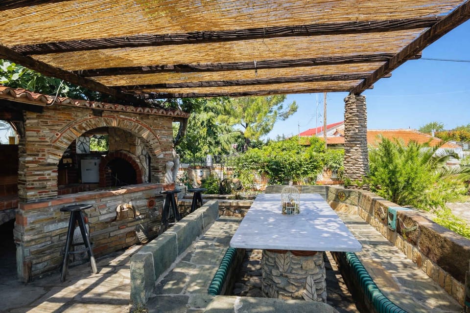 Large shaded outdoor dining table and BBQ area under the pergola, perfect for enjoying meals together during warm days.