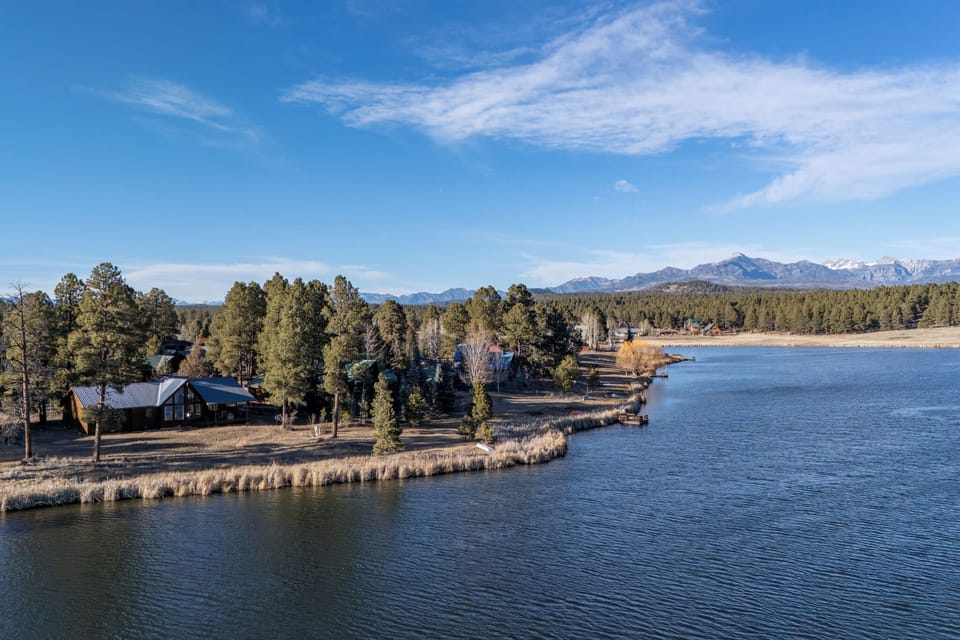 Scenic lakefront property nestled among towering pines with stunning mountain backdrop and pristine waters.