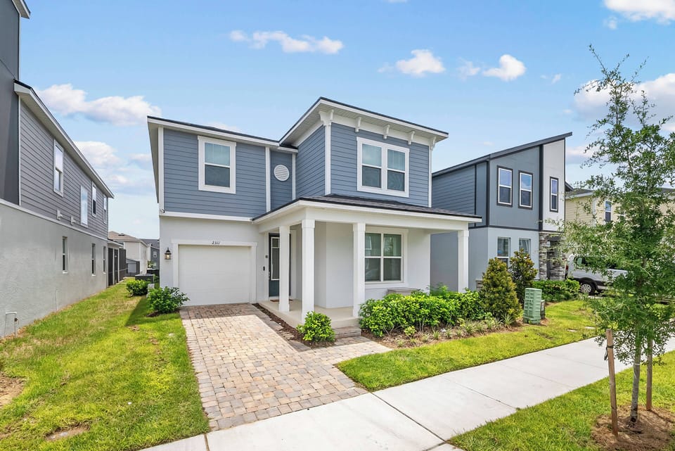 This charming home boasts a welcoming front porch and a soft blue exterior that complements the lovely landscaped garden, while a stone pathway leads you to an inviting entry, perfect for enjoying the fresh air.