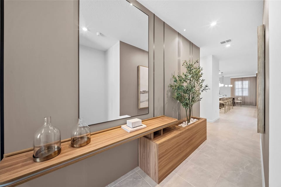 Enter a stylish hallway with a sleek wooden console, elegant decor, and a potted plant, creating a warm welcome. The soft lighting and neutral tones set a calm atmosphere, inviting you to discover more of the home.