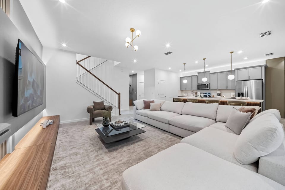 Welcome to a spacious living area with a plush sectional sofa and soft pillows inviting you to relax. Natural light fills the room, showcasing sleek wood accents and modern decor for a cozy yet stylish atmosphere.