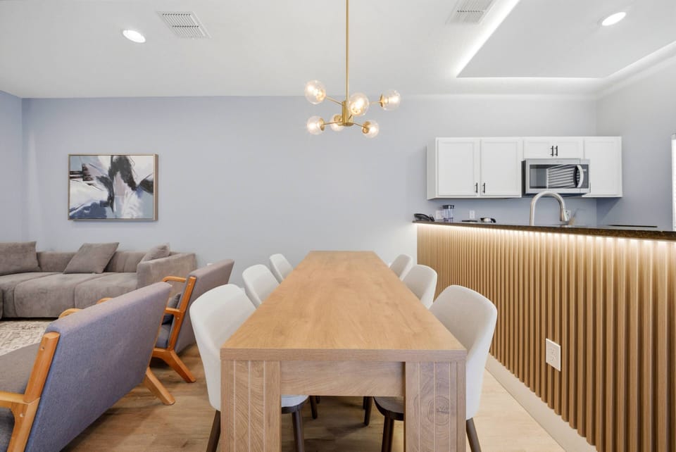 Enjoy meals at a beautiful wood table surrounded by soft, upholstered chairs in our stylish dining area. Warm lighting enhances the sleek kitchen, while cozy seating nearby invites you to relax and connect with loved ones.