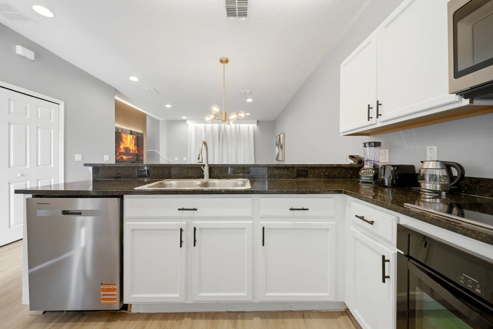Welcome to this bright kitchen, where sleek white cabinetry pairs beautifully with dark granite countertops. Modern appliances enhance both function and style, while soft lighting adds a warm atmosphere ideal for cooking.