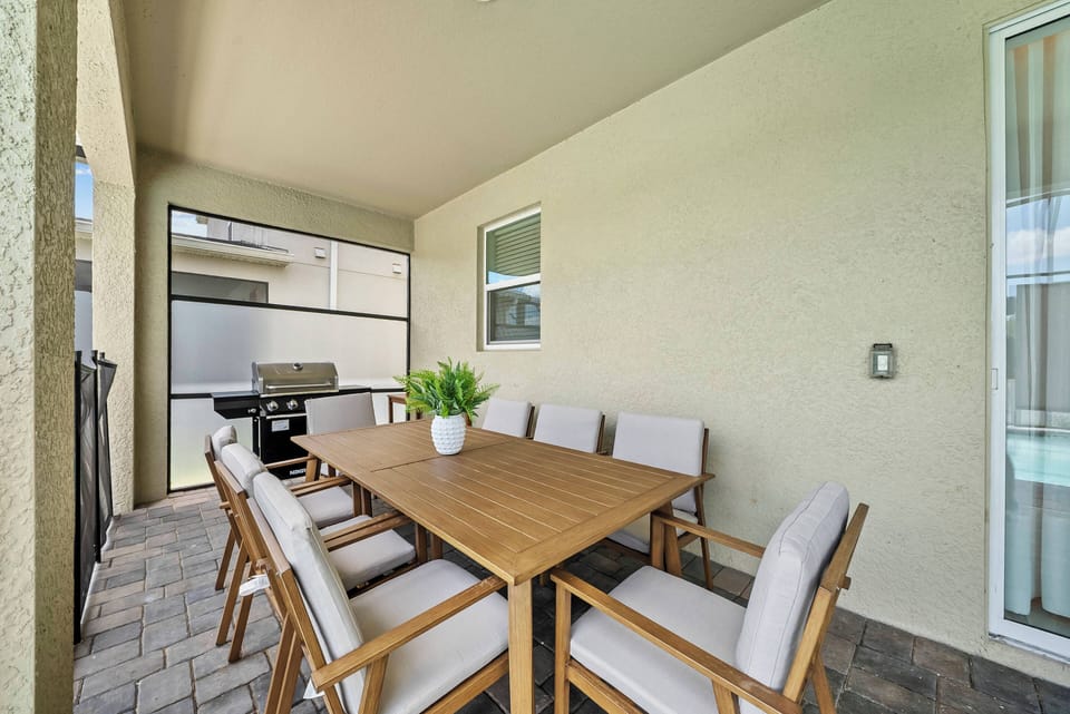 Enjoy al fresco dining at the spacious wooden table surrounded by cushioned chairs. The calming neutral decor sets the mood, while the nearby grill is perfect for casual cookouts with family and friends.