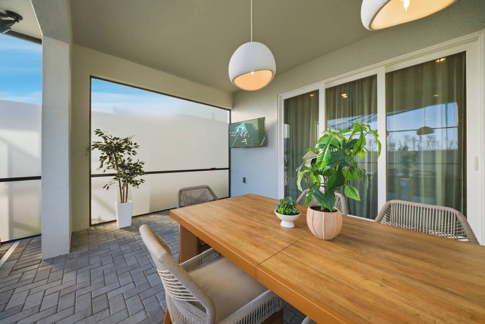Enjoy alfresco dining in our charming outdoor space with a natural wood table and stylish woven chairs. The warm glow of pendant lights creates a tranquil atmosphere, complemented by refreshing lush greenery around you.