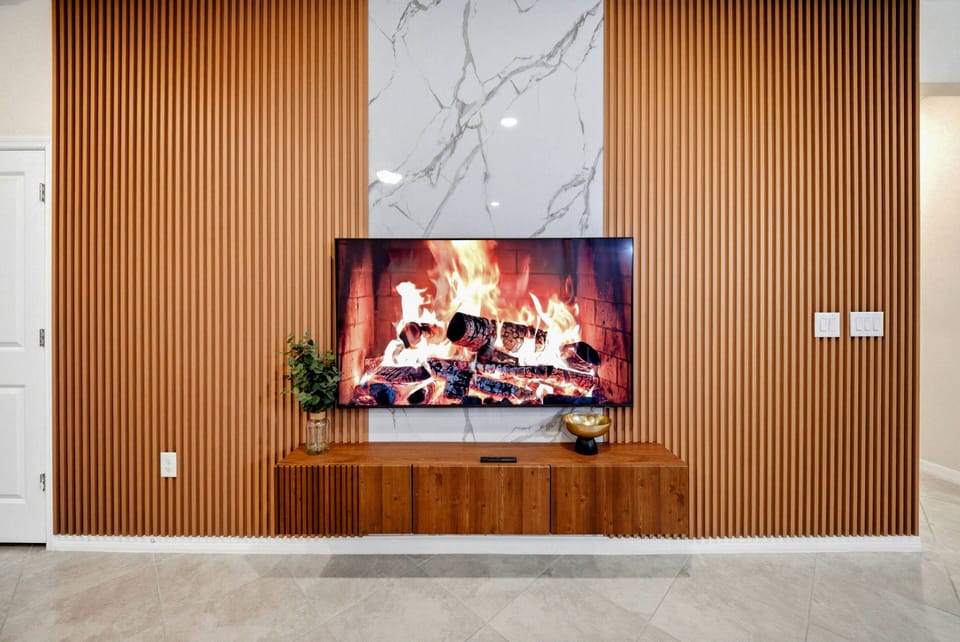 The warm wooden tones of the slatted wall create a cozy backdrop for movie nights, while the sleek marble feature catches the eye. With a stylish media console, this living area is ideal for relaxation and entertainment.