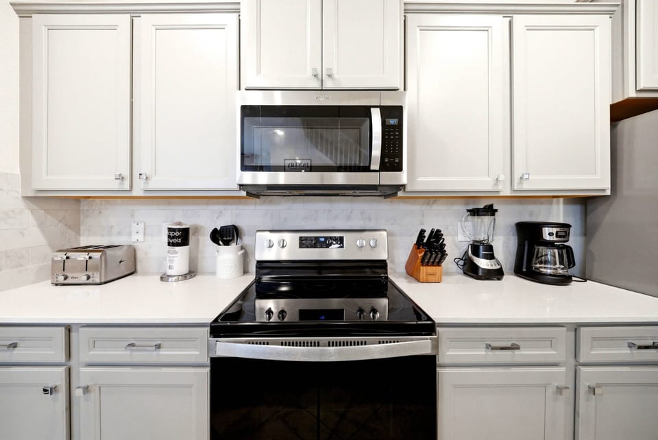 This stylish kitchen features sleek black appliances and crisp white cabinetry that contrast beautifully with light granite countertops. Enjoy cooking in a well-organized space with modern tools, all under soft, inviting lighting.