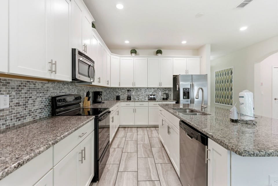 Welcome to a bright kitchen with sleek white cabinetry and a beautiful mosaic backsplash, ideal for your culinary adventures. Enjoy the spacious layout, modern stainless steel appliances, and elegant granite countertops for meal.