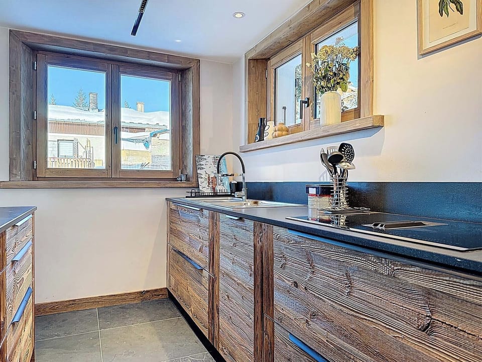 Contemporary open-plan kitchen with premium appliances and rustic wood finishes, perfectly designed for convivial moments after a day on the pistes.