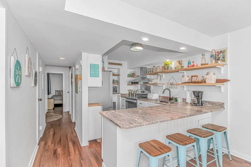 Fully equipped coastal kitchen with large breakfast bar and seating for four.
