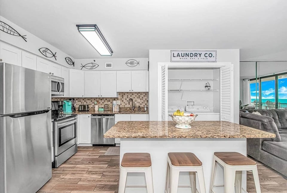 Fully equipped kitchen with island seating & in-unit laundry.