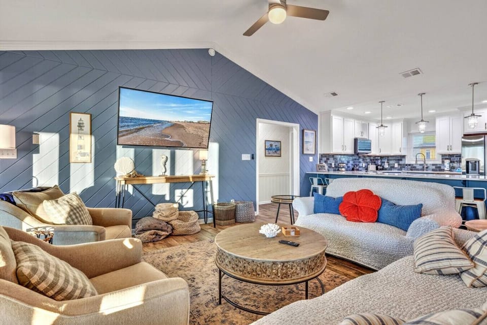 This stunning open-concept loft features a spacious living area with coastal décor, a full kitchen, and beautiful blue shiplap accents throughout.