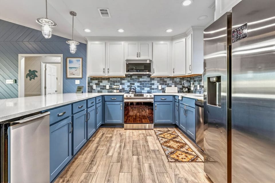 This chef`s kitchen features stunning blue cabinetry, stainless steel appliances, and beautiful tile backsplash that`ll make you never want to leave.