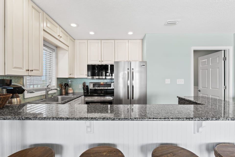 Gather around the island for drinks, snacks, or stories. This spacious bar top is perfect for mingling after a day at the beach.