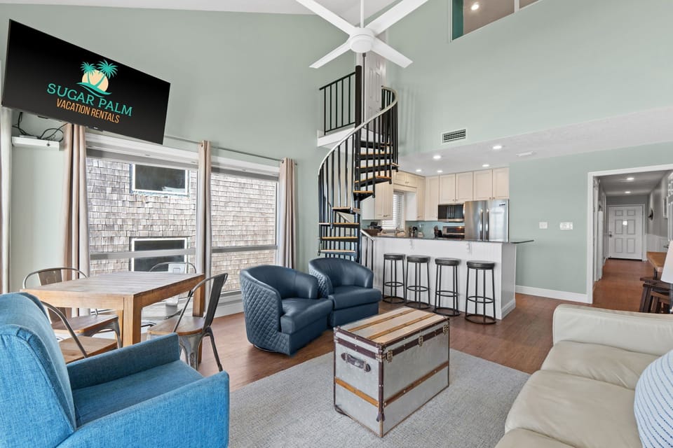 Bright, open, and designed with comfort in mind – this beachfront living room features coastal décor, high ceilings, and two sliding glass doors that bring the outside in.