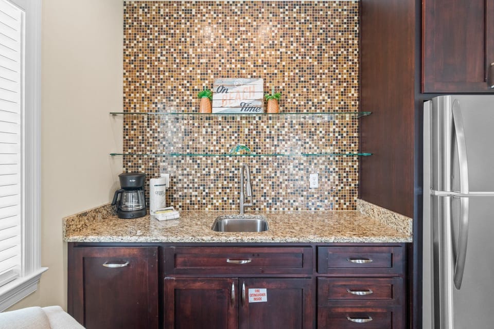 Downstairs living room features a modern wet bar with sink and full size refrigerator