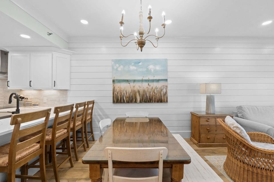 Bright dining space and kitchen with shiplap walls, coastal lighting, and ample seating for meals, games, or evening conversations.