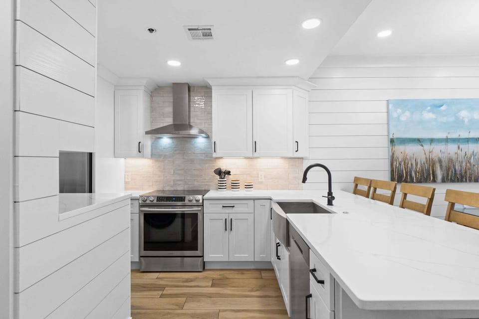 Bright, remodeled kitchen with quartz countertops, stainless steel appliances, and spacious island seating—perfect for casual meals and gathering together.