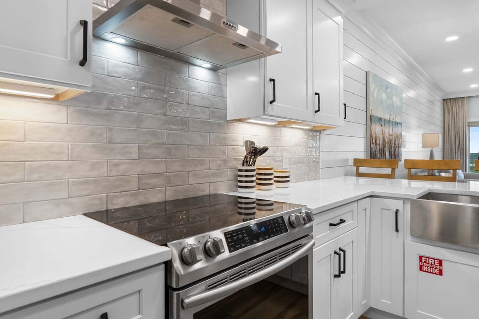 Bright, remodeled kitchen with quartz countertops, stainless steel appliances, and spacious island seating—perfect for casual meals and gathering together.