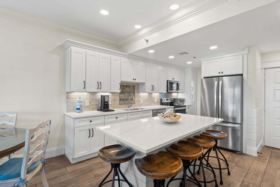 Bright, remodeled kitchen featuring stainless steel appliances, quartz countertops, and island seating for casual dining.