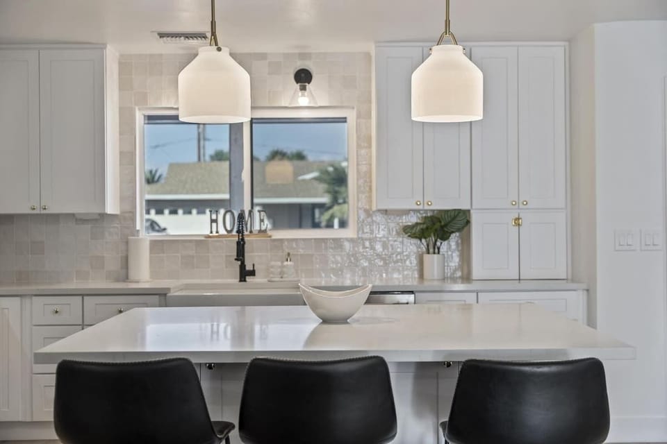 Bright, modern kitchen with a spacious island, sleek white cabinetry and stainless steel appliances.