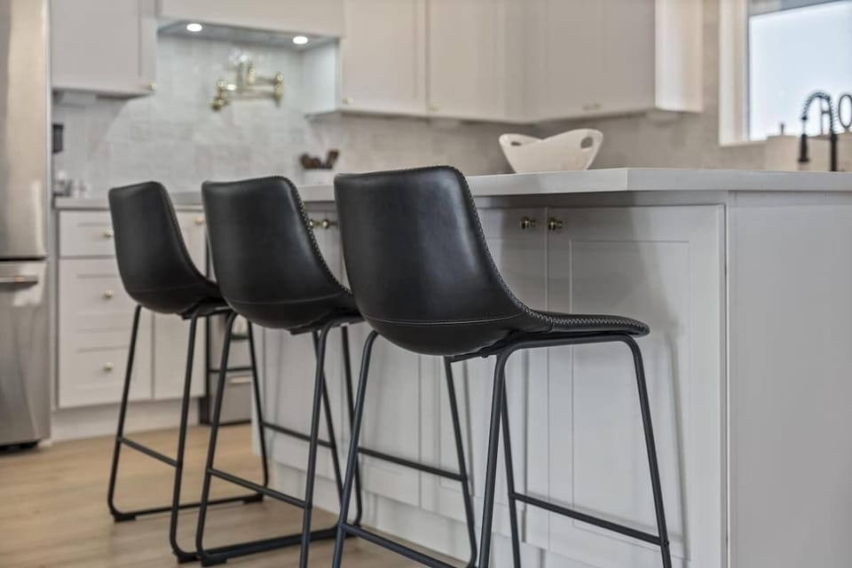 Bright, modern kitchen with a spacious island, sleek white cabinetry and stainless steel appliances.