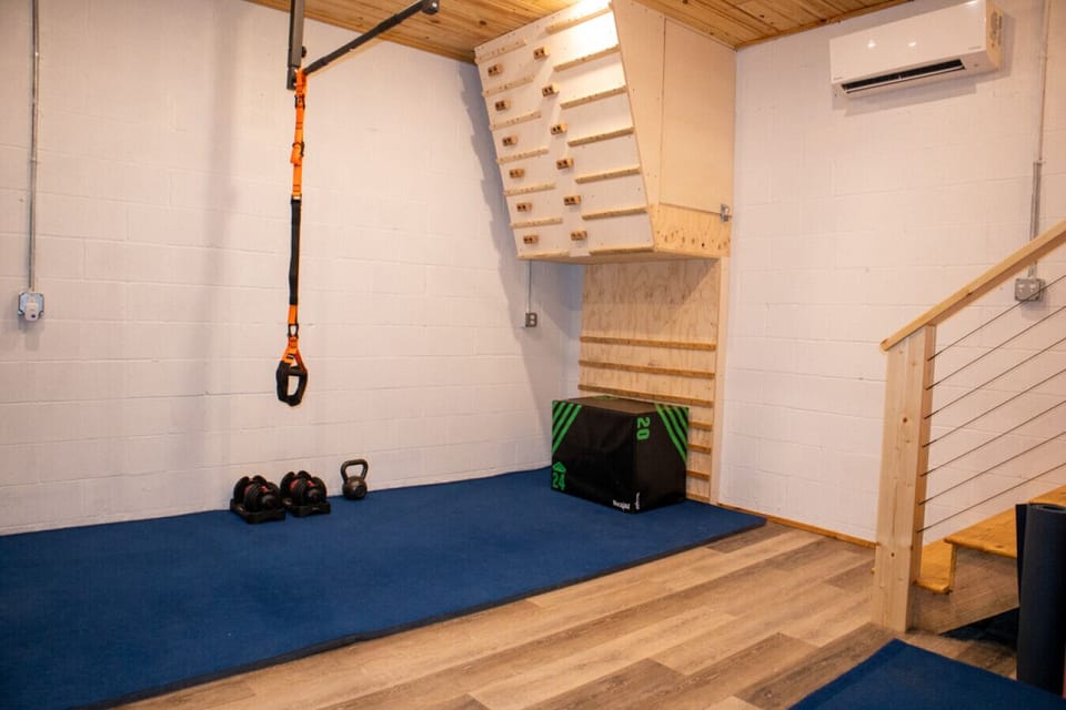 Private workout space with climbing wall, TRX straps, weights, and laundry for active Red River Gorge guests. 💪