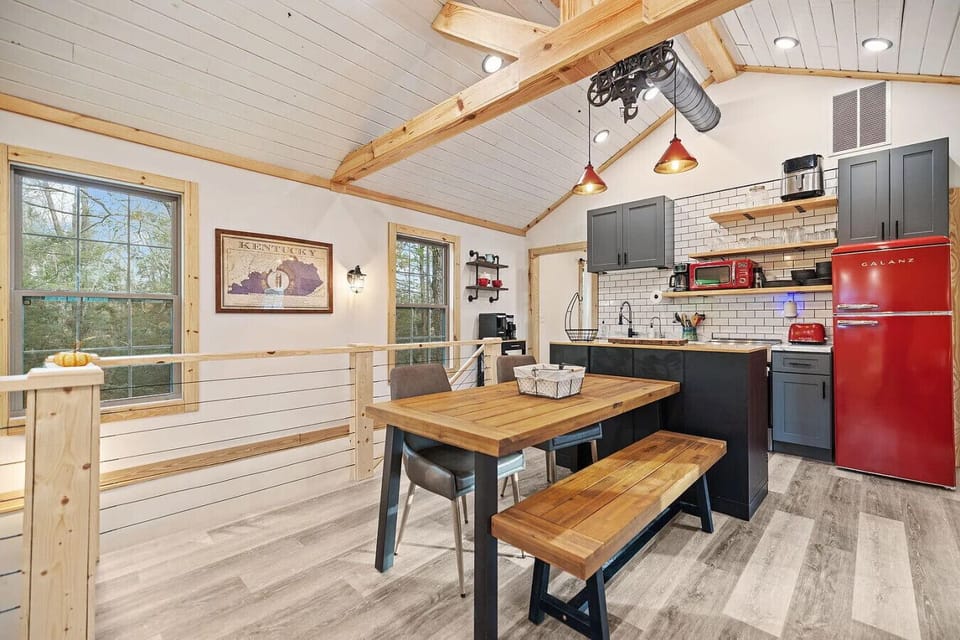 Bright open-concept kitchen and dining area with vaulted ceilings, modern finishes, and retro-style fridge.