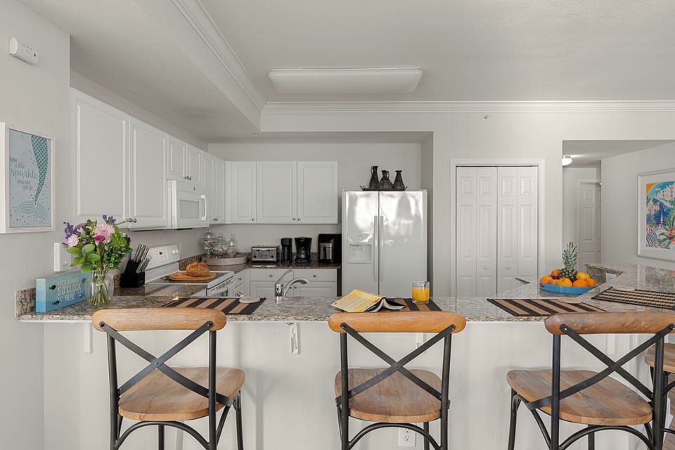 Granite breakfast bar with three stools overlooking the fully equipped kitchen—ideal for morning coffee, casual meals, or evening drinks.
