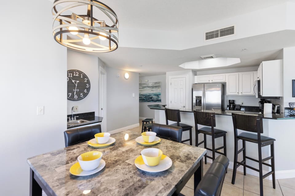 Your fully equipped kitchen flows seamlessly into a stylish dining area, where modern appliances meet warm marble surfaces under elegant lighting.