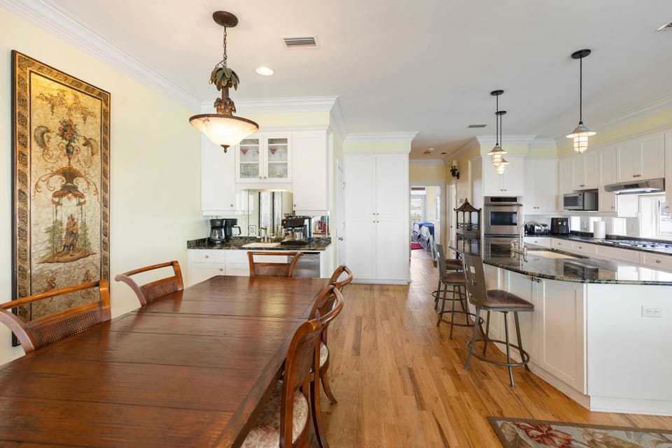 Your open-concept kitchen flows seamlessly into the dining area, featuring gleaming granite countertops, white cabinetry, and warm hardwood floors that invite memorable meals.