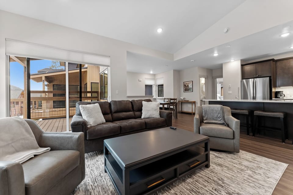 Unwind in your spacious living room where modern comfort meets mountain style, featuring plush seating and an open kitchen perfect for gathering.